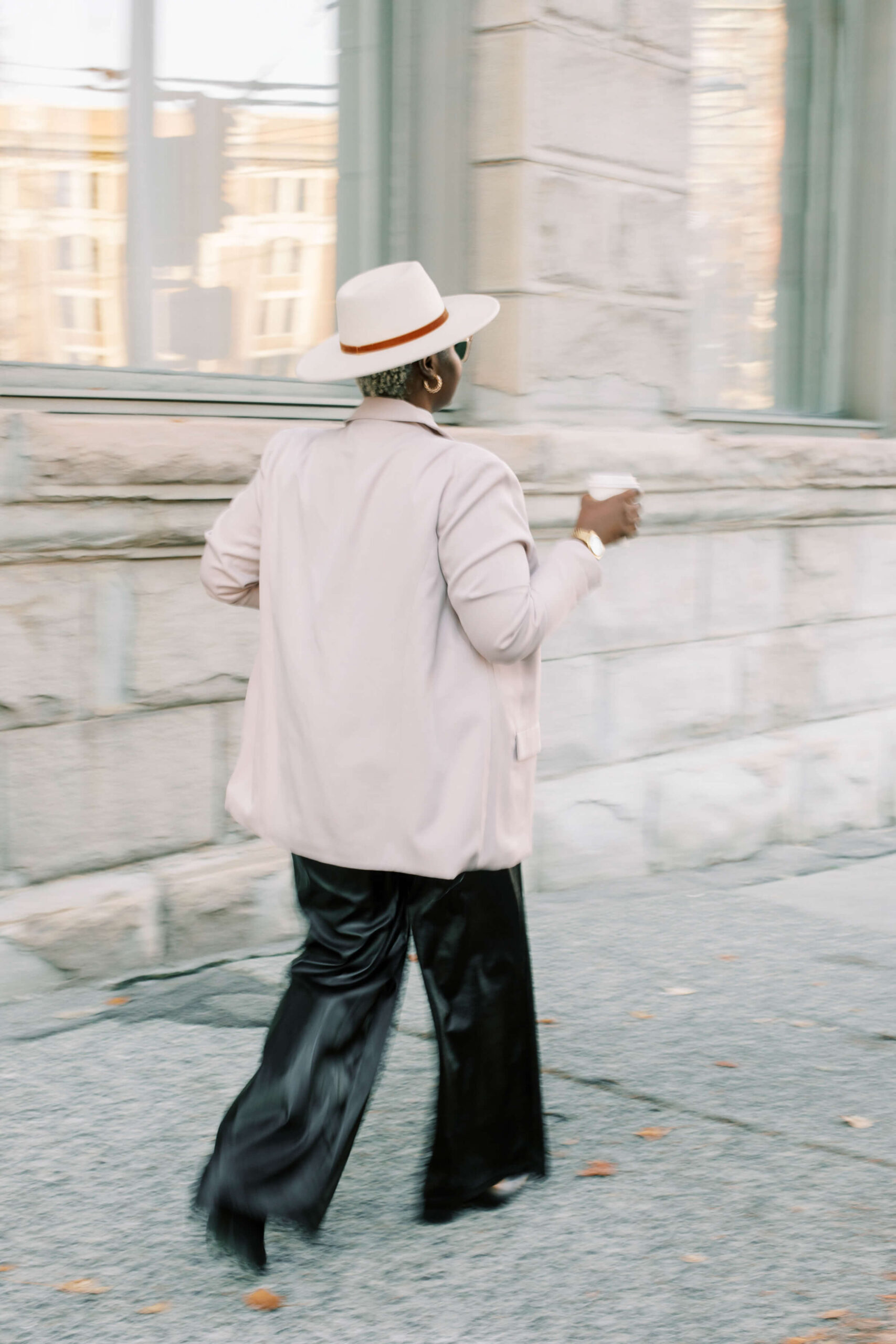 Black woman walking in city while holding coffee cup